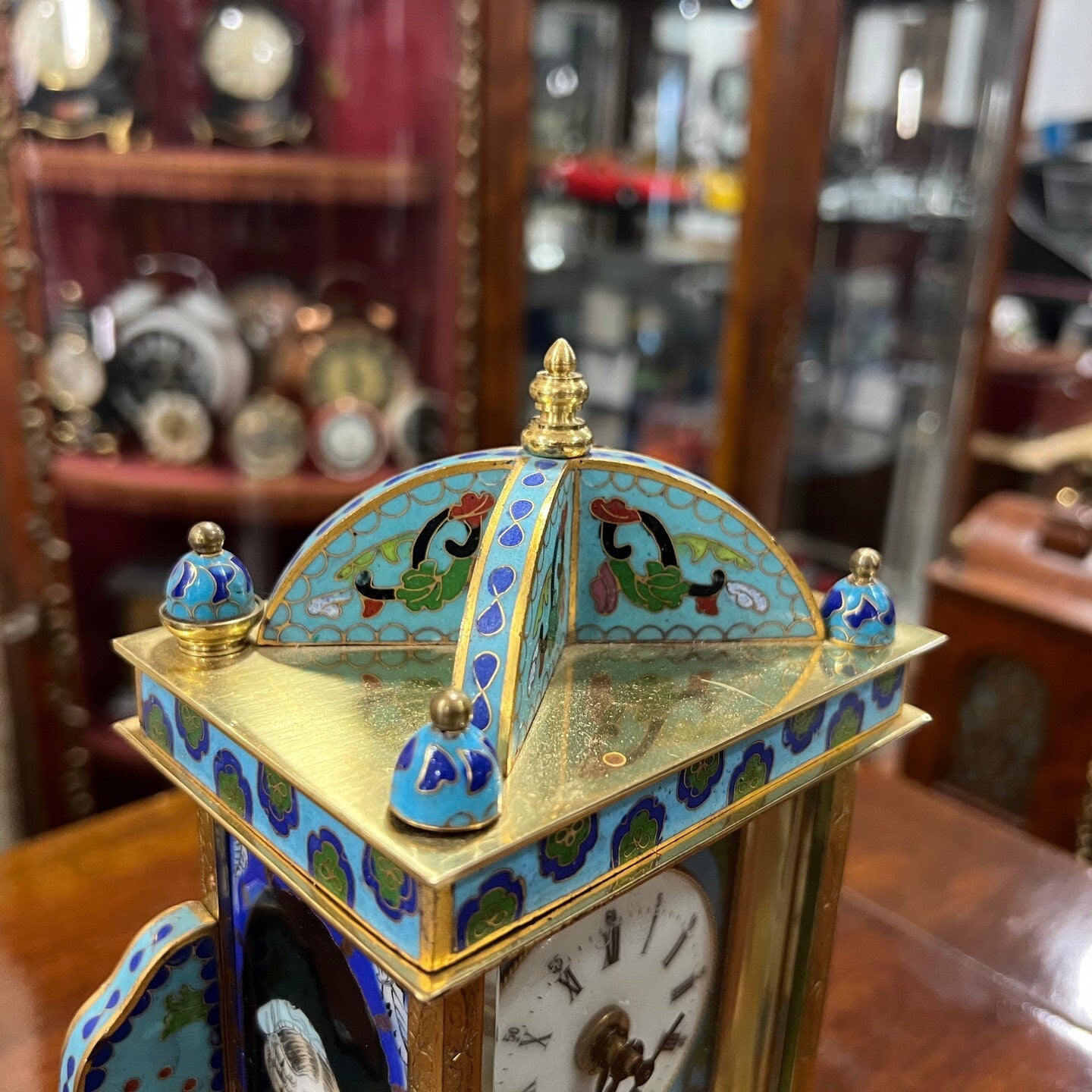 Close-up of a collectible antique enamel brass quartz clock with intricate design on top in perfect condition