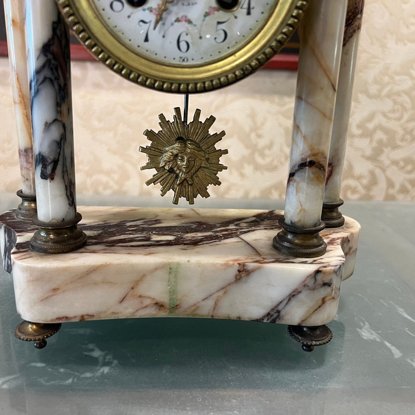 Detailed view of antique French marble base mantel clock with sun pendulum