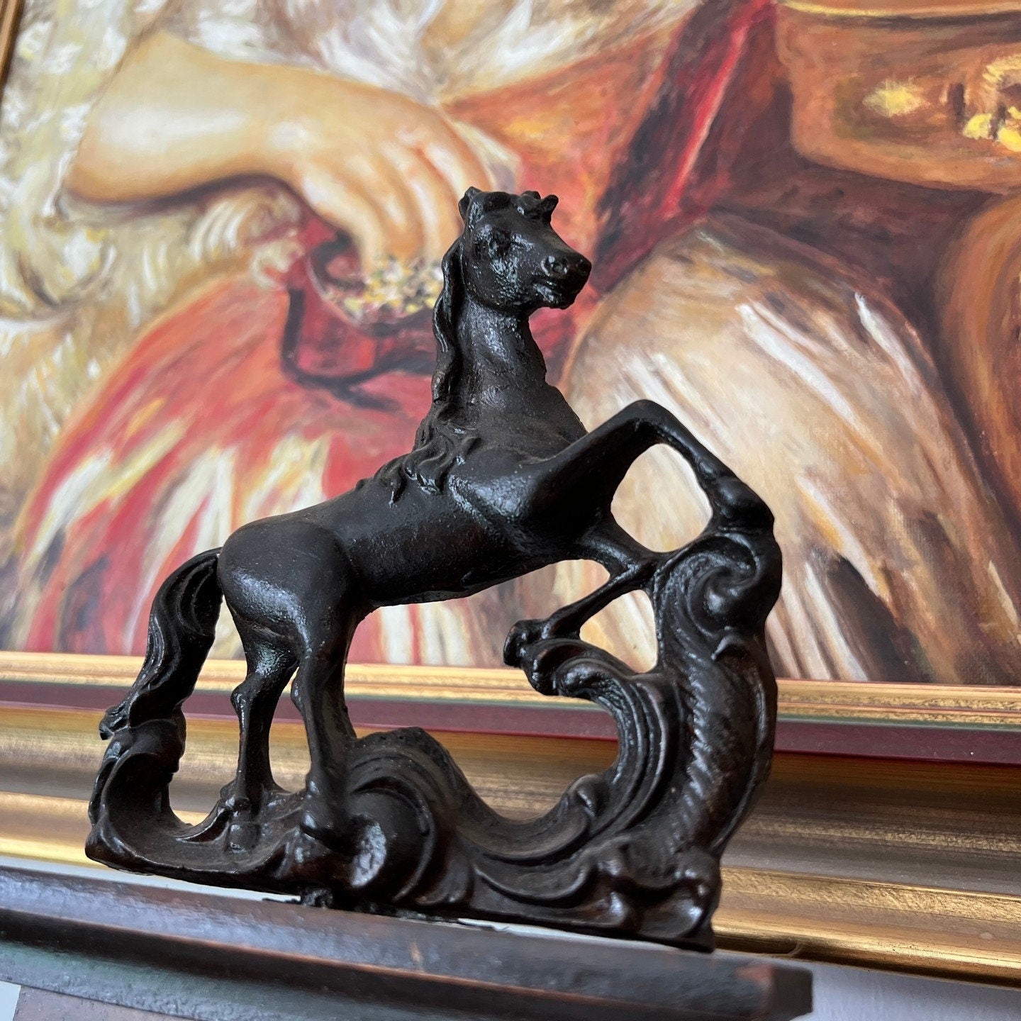 Antique black horse figurine in front of a colorful background painting.